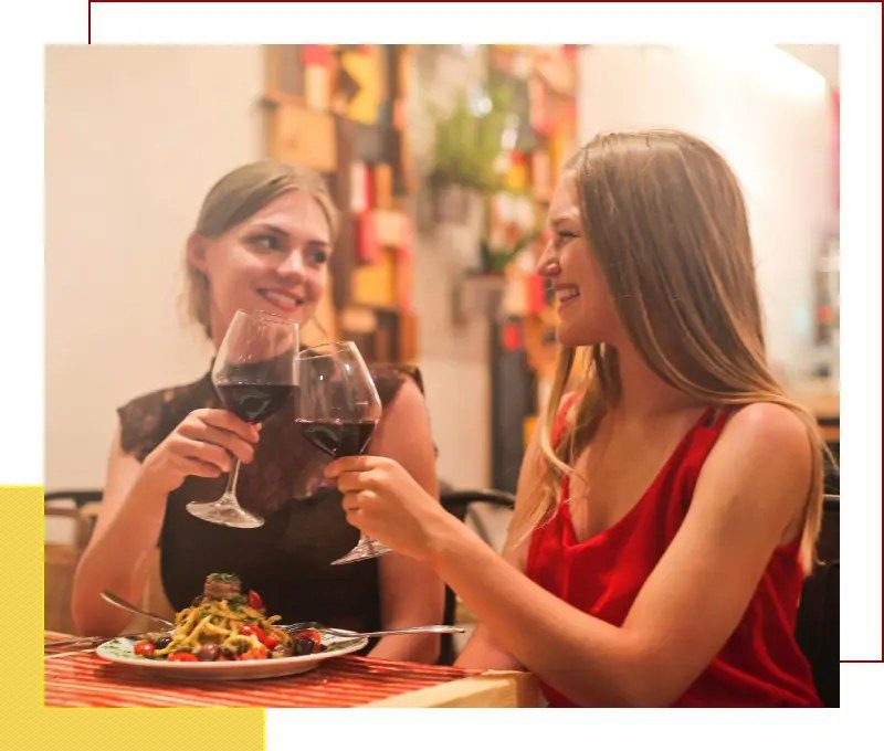 Two women are enjoying wine while dining at a restaurant